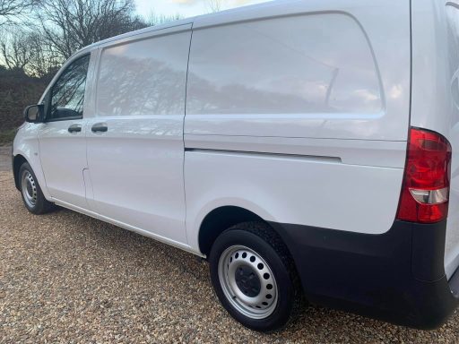 White van parked on gravel with a clear sky in the background.